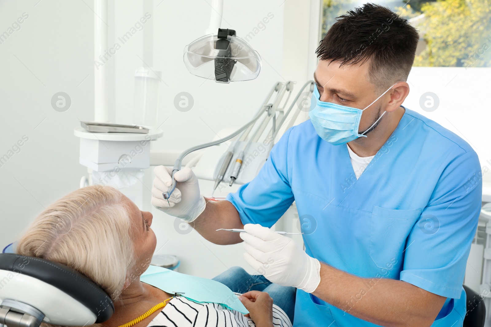 Photo of Professional dentist working with patient in clinic