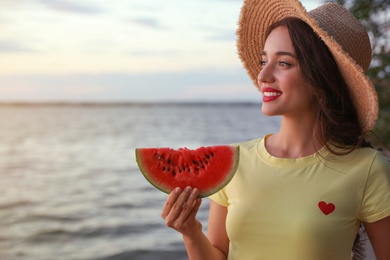 Photo of Beautiful young woman with watermelon near river. Space for text