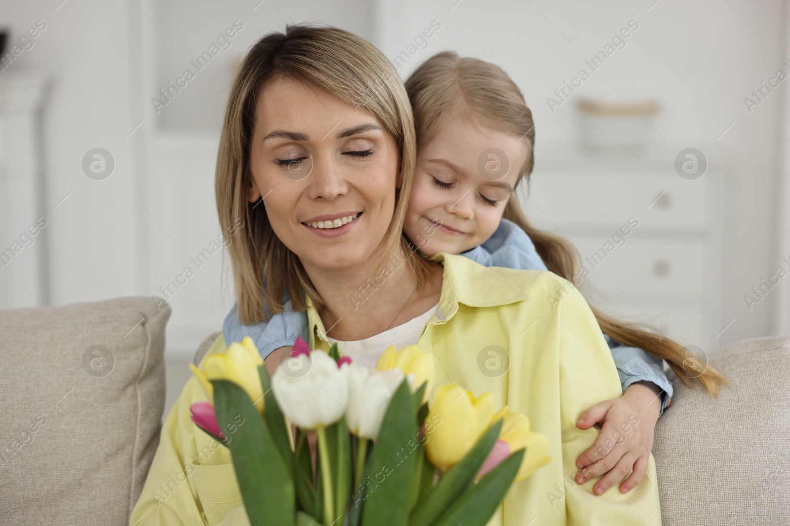 Photo of Little daughter congratulating her mom with bouquet of beautiful tulips at home. Happy Mother's Day