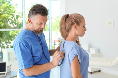 Male medical assistant examining female patient in clinic