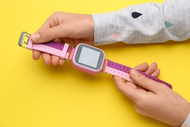 Girl with stylish smart watch on yellow background, closeup