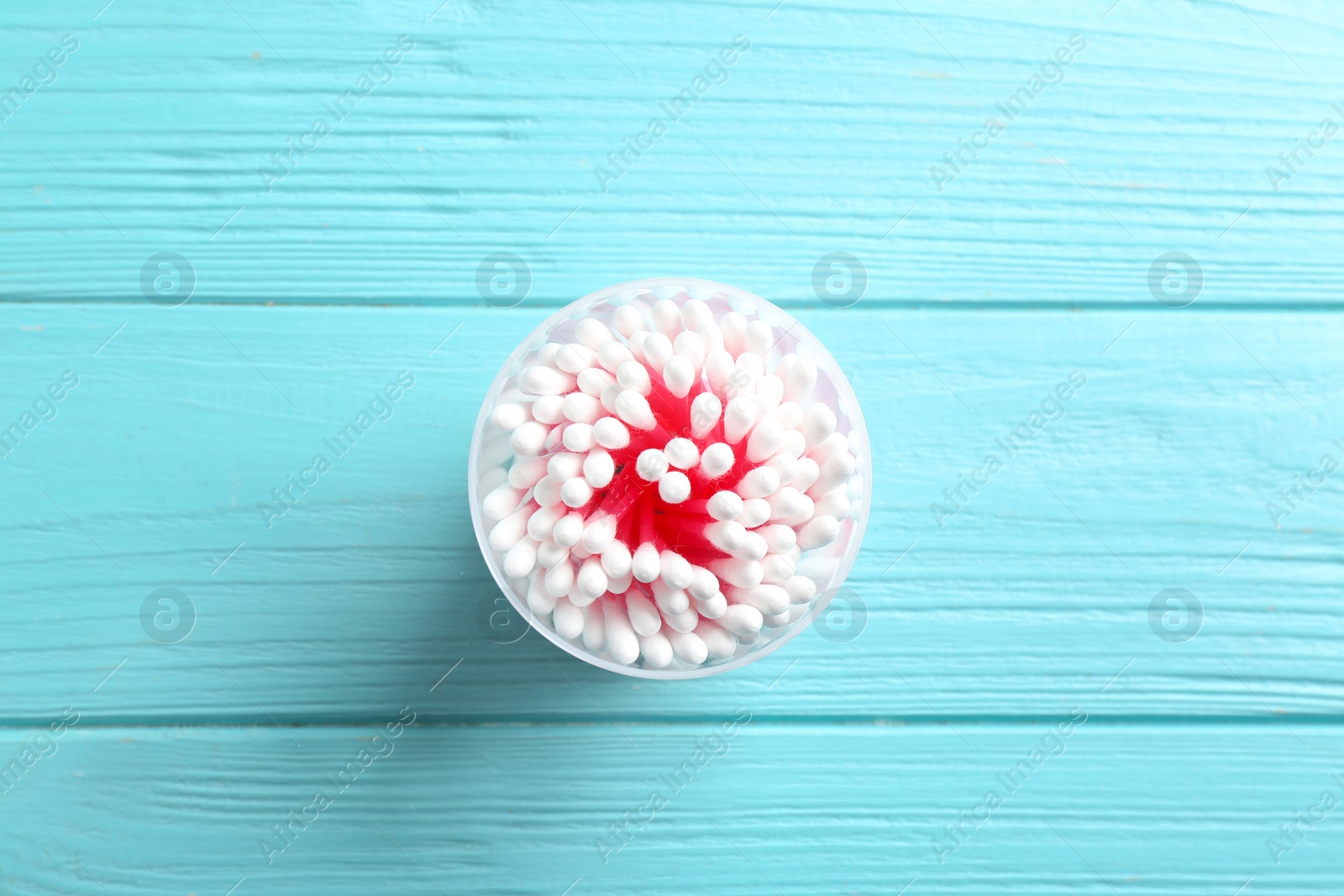 Photo of Plastic container with cotton swabs on wooden background, top view