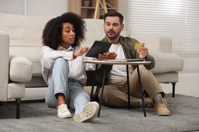 Photo of Confused couple with calculator and credit card planning budget at home. Debt problem