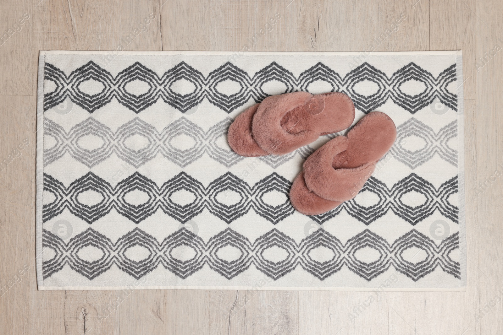 Photo of Soft bath mat and slippers on floor, top view