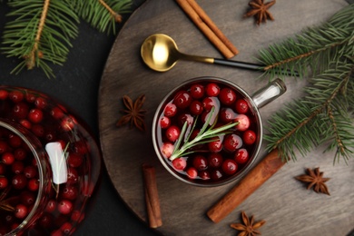Photo of Tasty hot cranberry tea with rosemary, anise and cinnamon on black table, flat lay