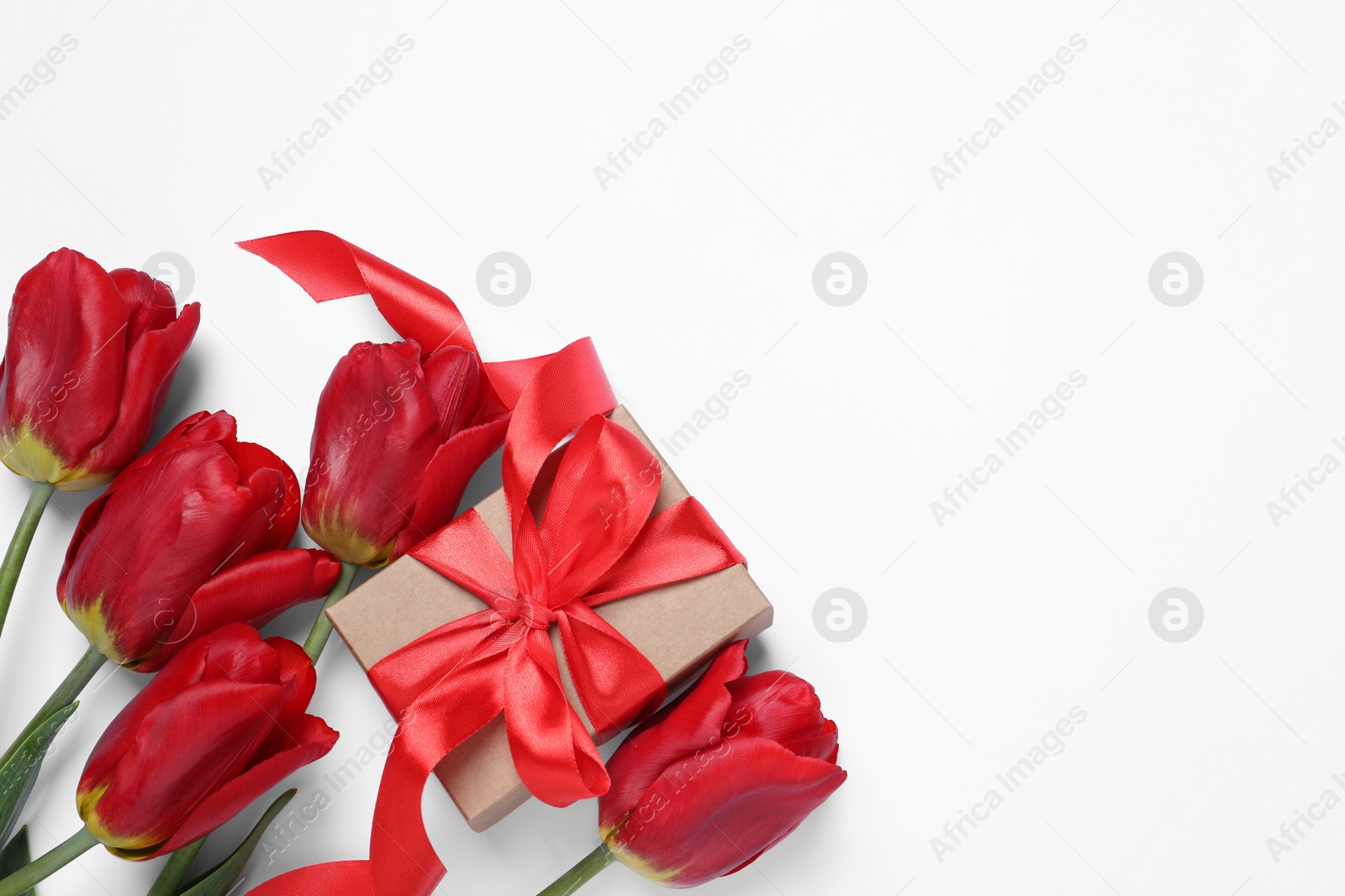 Photo of Beautiful gift box and red tulip flowers on white background, flat lay. Space for text