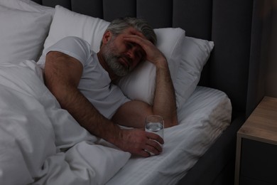 Photo of Mature man suffering from headache in bed at night