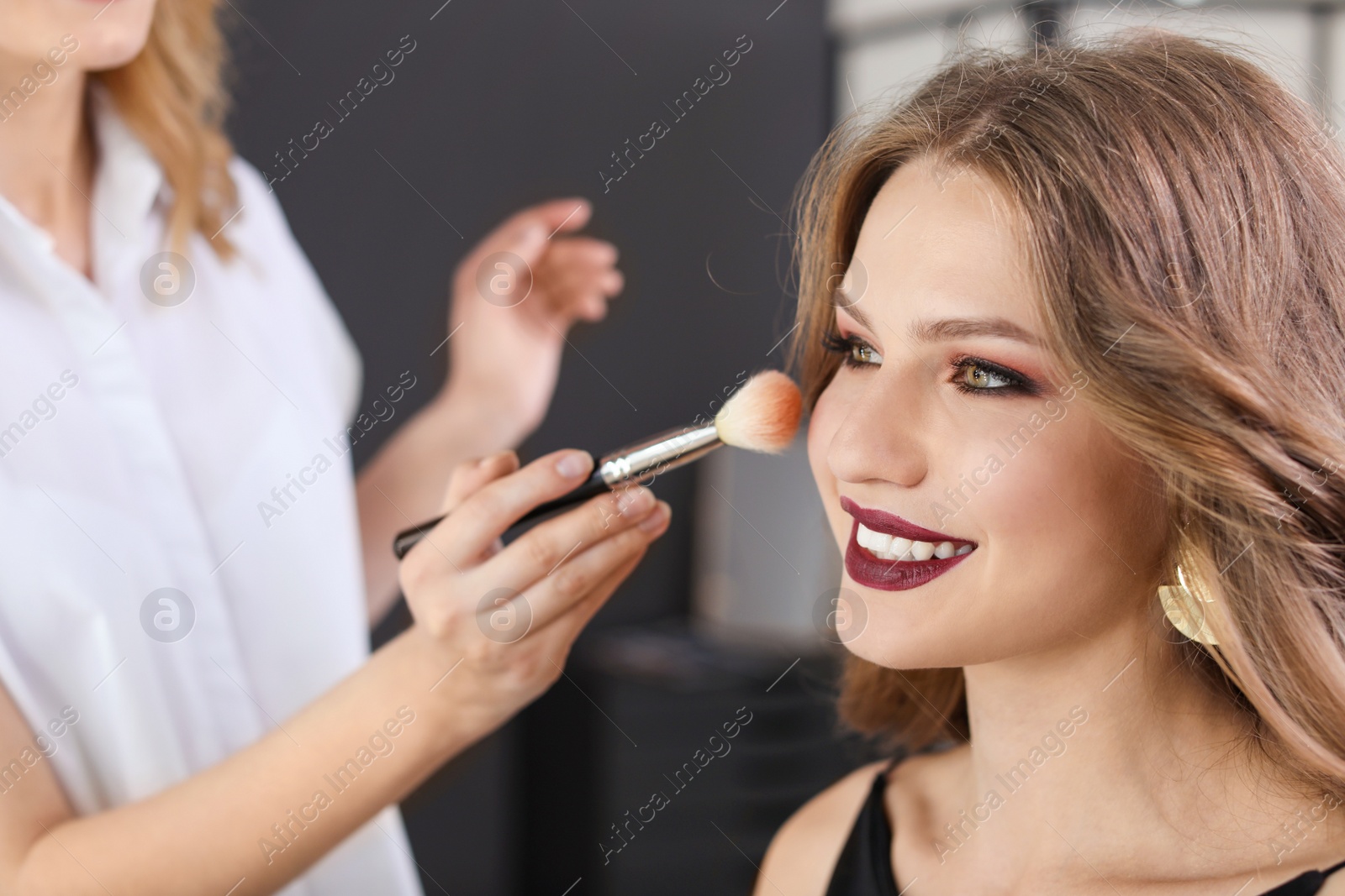 Photo of Professional makeup artist working with client in dressing room