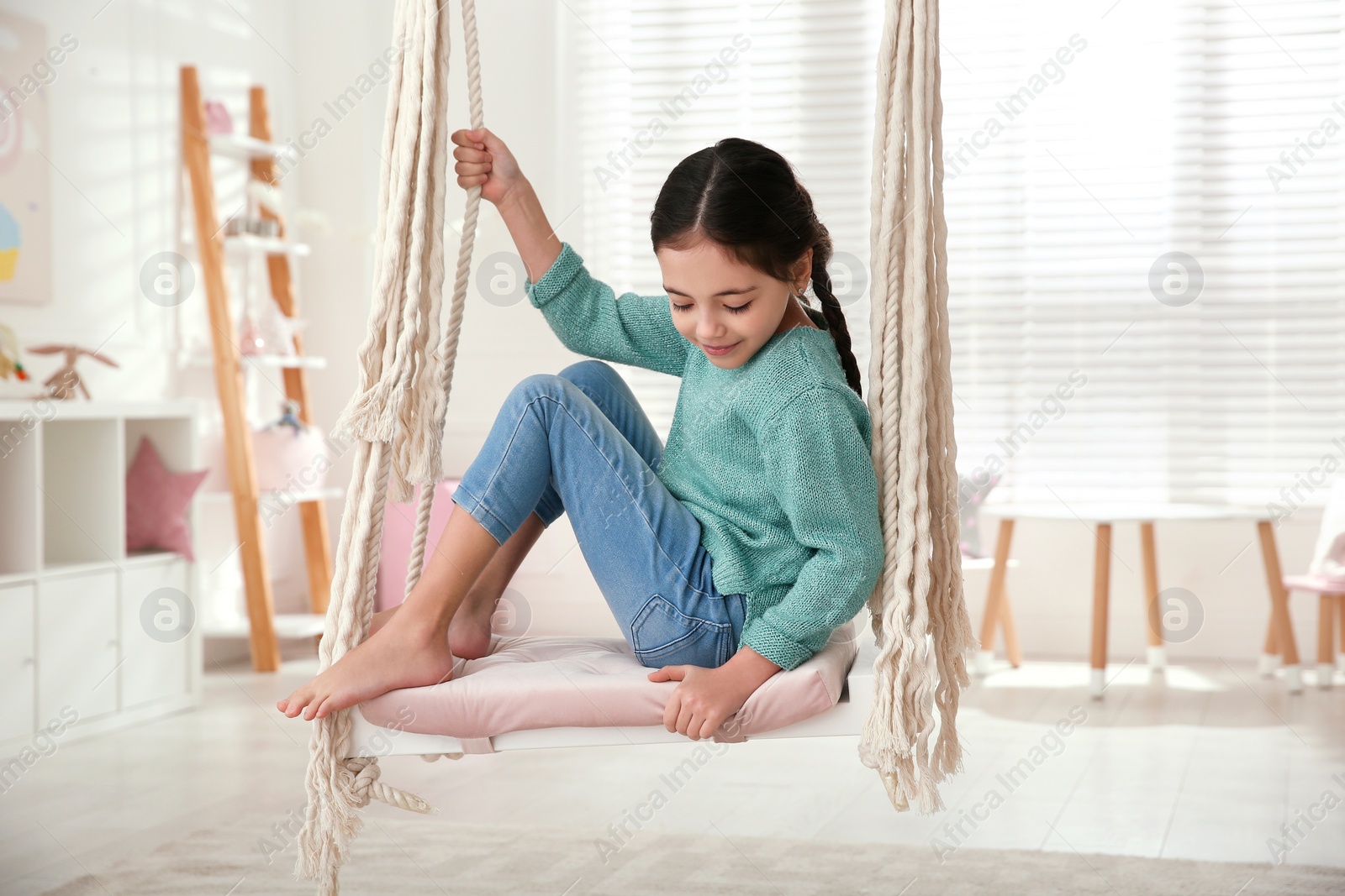 Photo of Cute little girl playing on swing at home