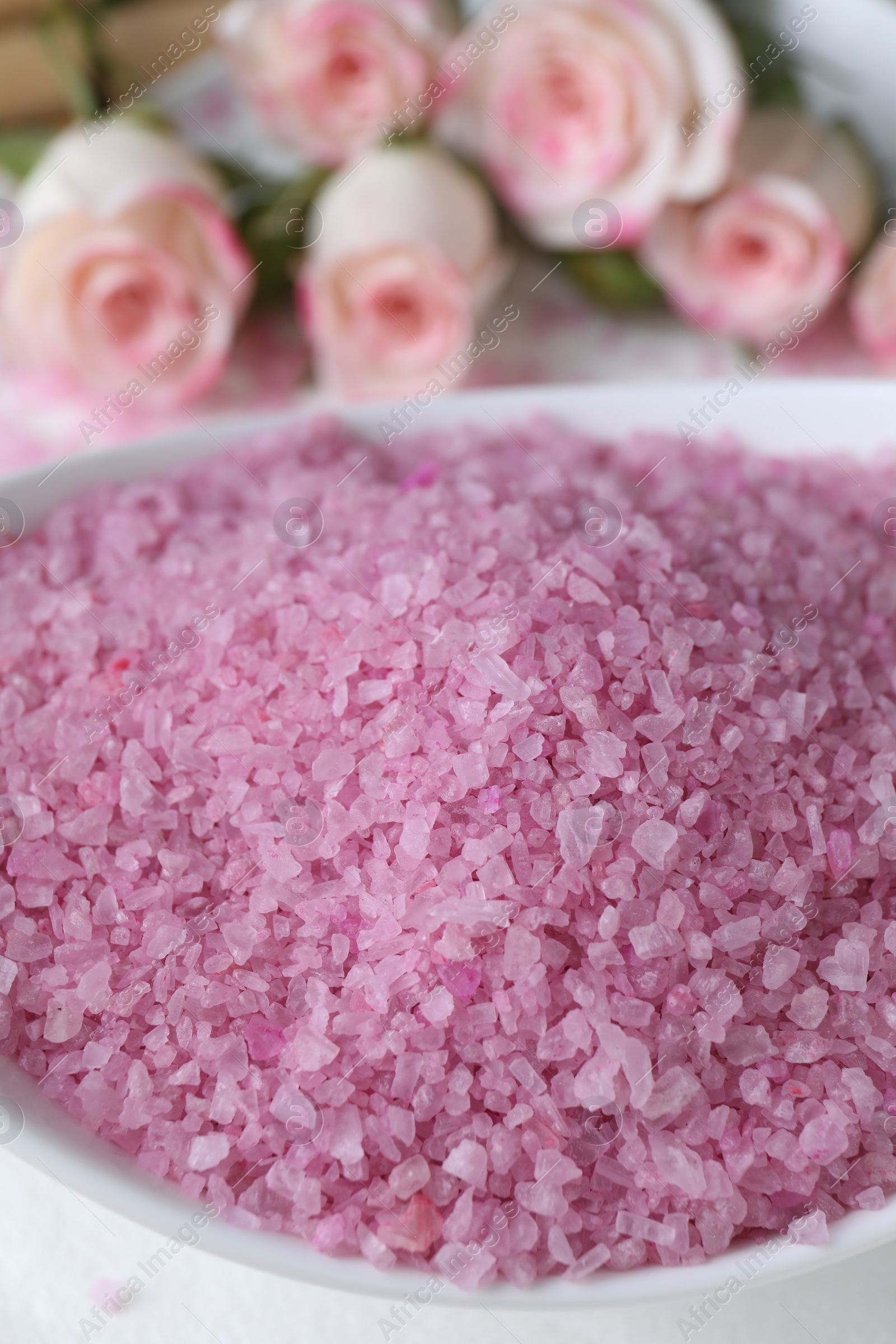 Photo of Bowl with pink sea salt on blurred background, closeup