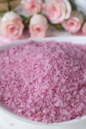 Bowl with pink sea salt on blurred background, closeup
