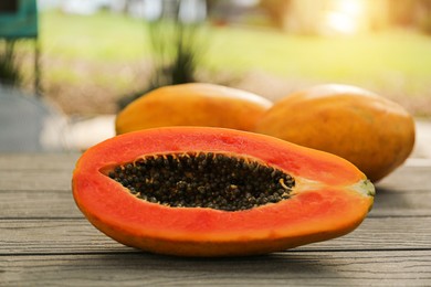 Photo of Fresh ripe papaya fruits on wooden table outdoors