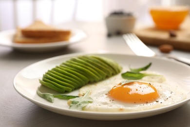 Tasty breakfast with fried egg and avocado on table, closeup