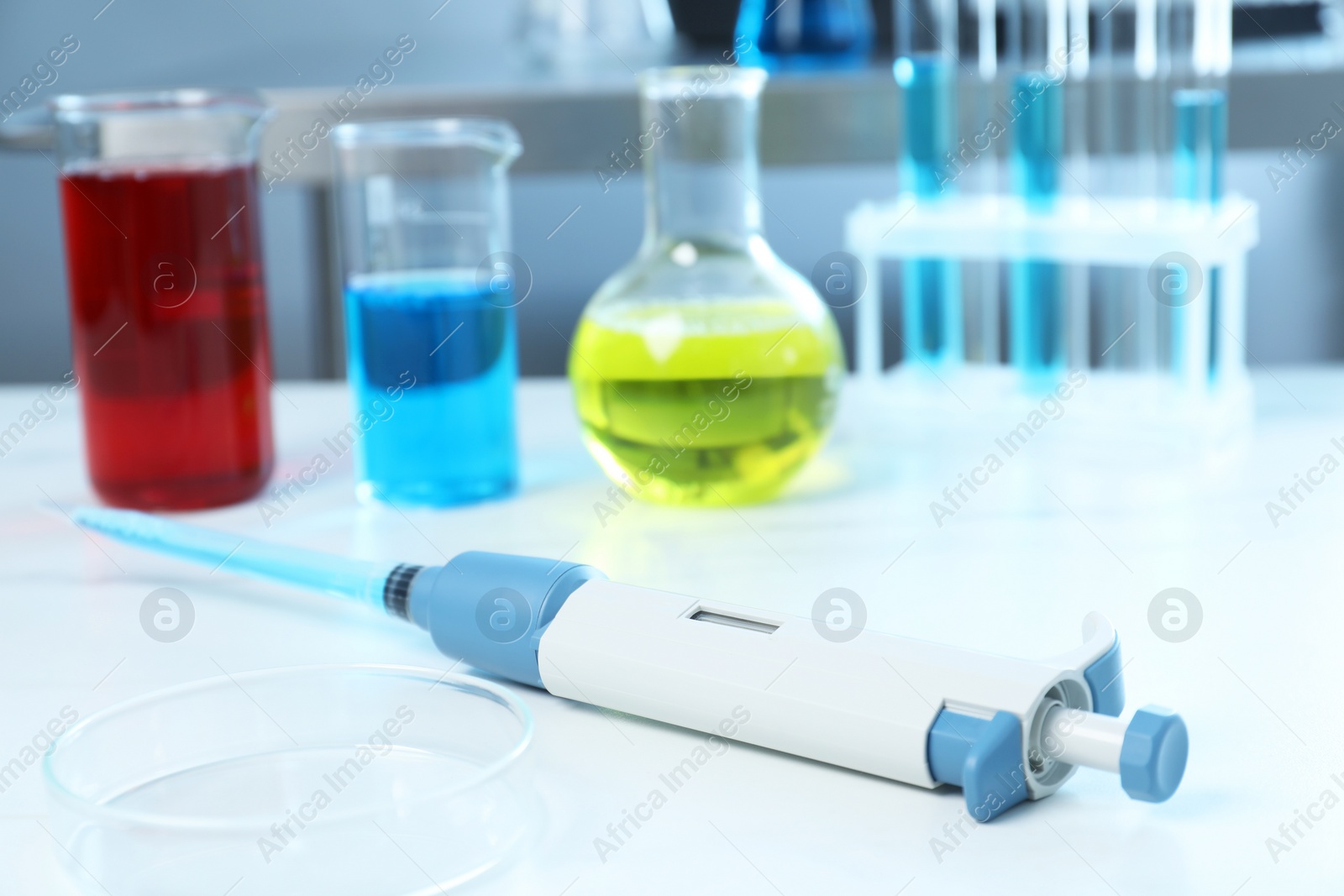 Photo of Laboratory analysis. Micropipette, petri dish and other glassware on white marble table, closeup