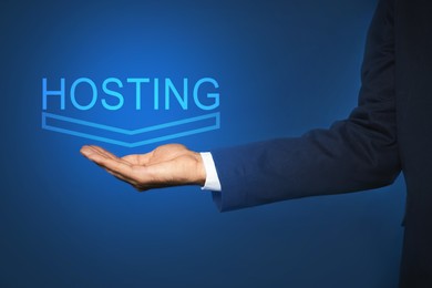 Image of Man showing virtual model of word HOSTING against blue background, closeup