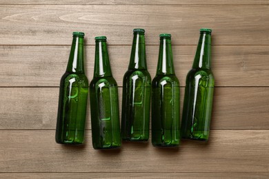Glass bottles of beer on wooden background, flat lay