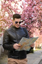 Happy male tourist with map on city street