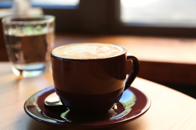 Photo of Aromatic coffee on wooden table in cafe, closeup
