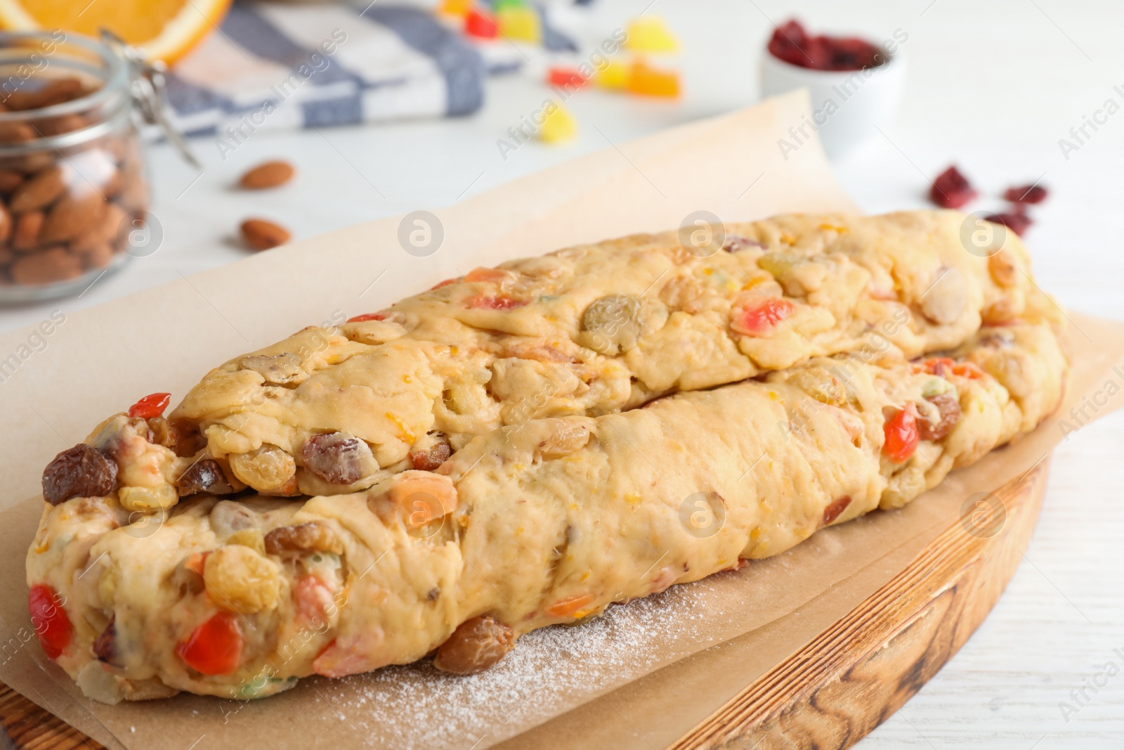 Photo of Unbaked Stollen with candied fruits and raisins on white wooden table, closeup
