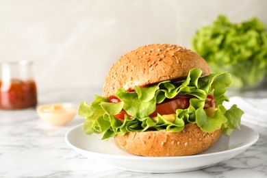 Photo of Tasty burger with lettuce and tomato in plate on table. Space for text