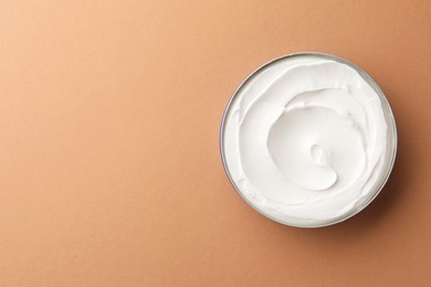 Jar of face cream on beige background, top view. Space for text