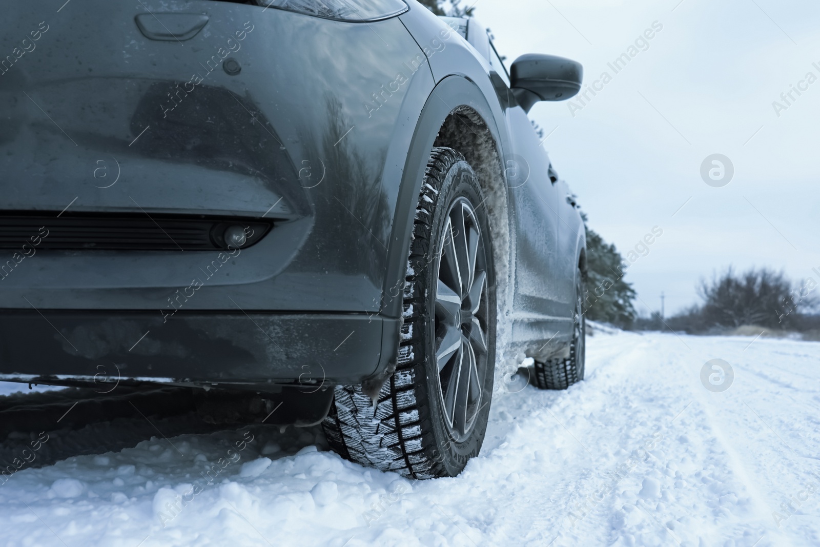 Photo of Snowy country road with car on winter day, closeup. Space for text