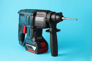 Photo of Modern electric power drill on light blue background
