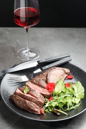 Photo of Delicious grilled beef meat served with greens and wine on grey table