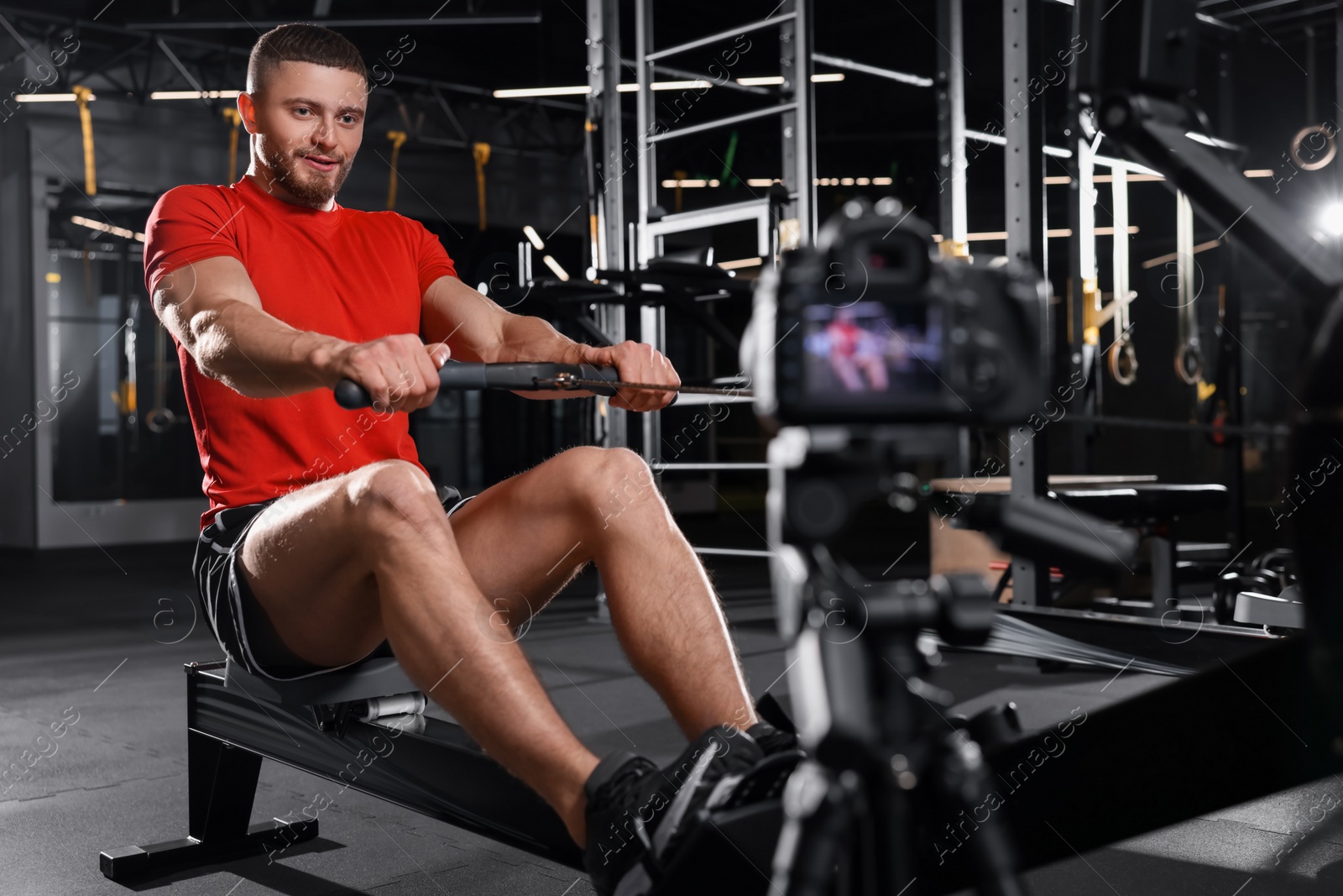 Photo of Man recording workout on camera at gym. Online fitness trainer