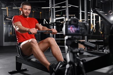 Man recording workout on camera at gym. Online fitness trainer