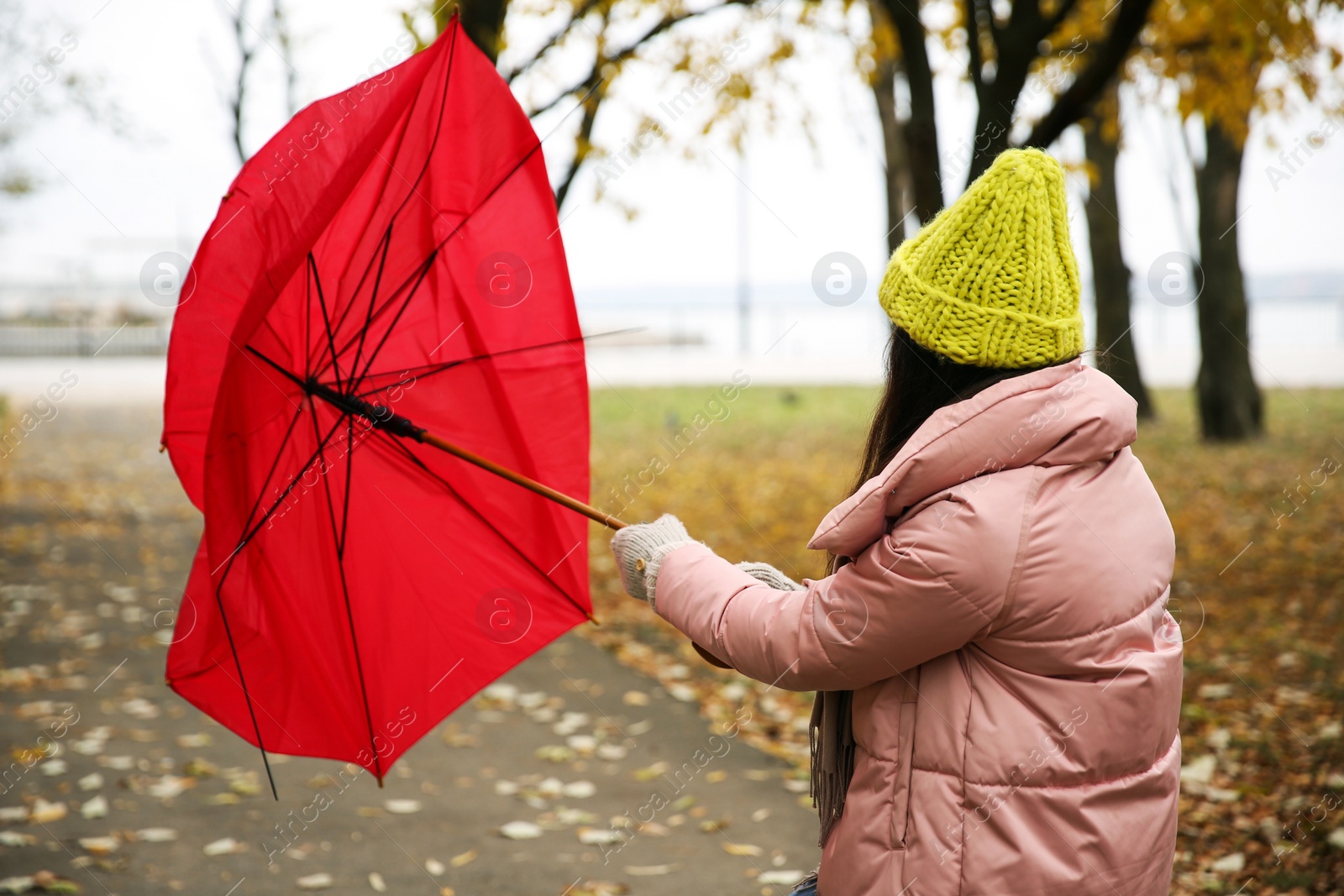 Photo of Woman with red umbrella caught in gust of wind outdoors