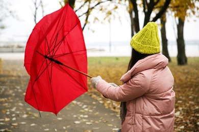 Photo of Woman with red umbrella caught in gust of wind outdoors