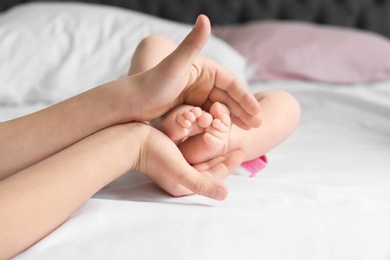 Photo of Child holding feet of cute little baby in hands, closeup