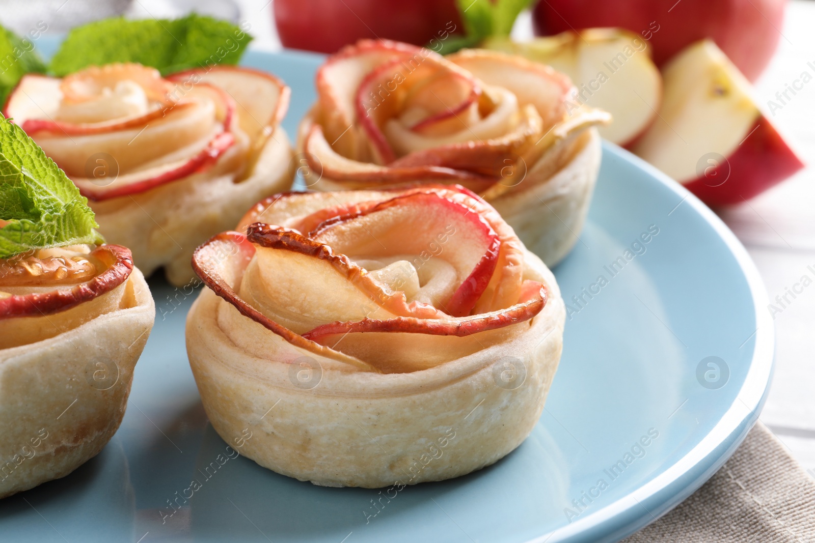 Photo of Freshly baked apple roses on plate, closeup. Beautiful dessert