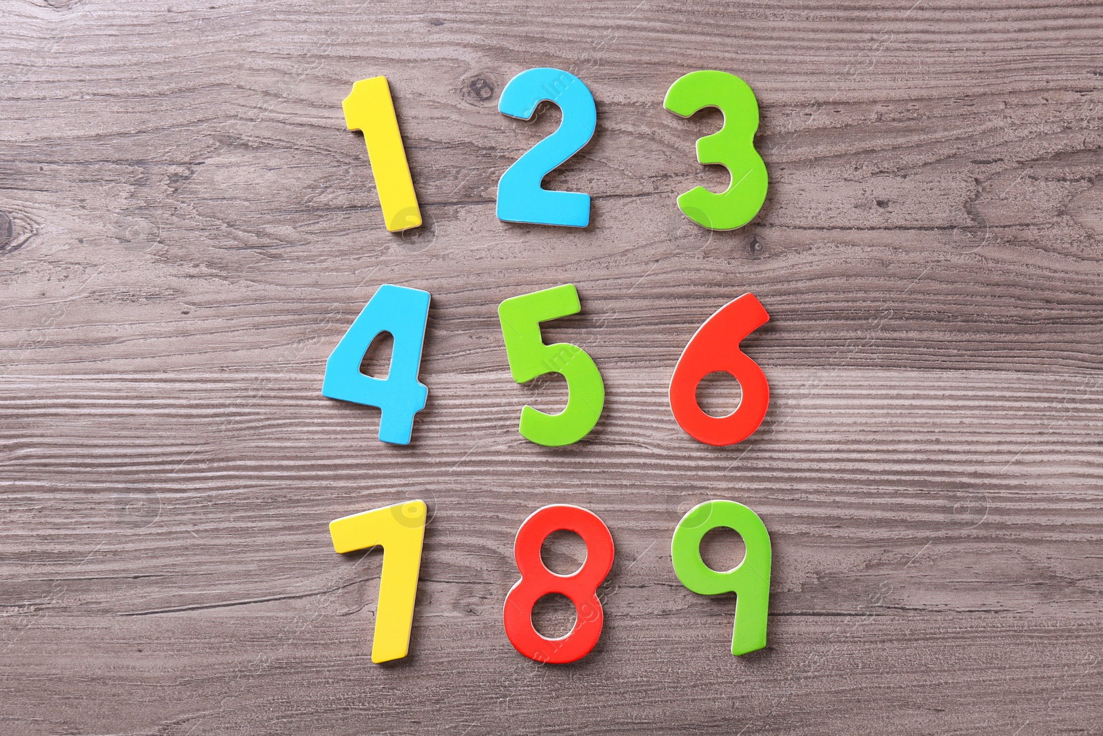 Photo of Colorful numbers on wooden school desk, flat lay