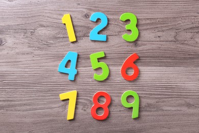 Photo of Colorful numbers on wooden school desk, flat lay