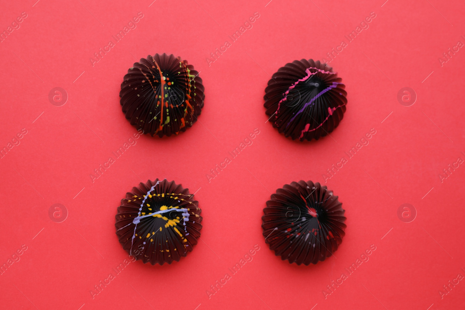 Photo of Different tasty chocolate candies on red background, flat lay