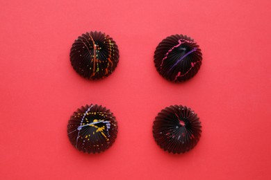 Photo of Different tasty chocolate candies on red background, flat lay