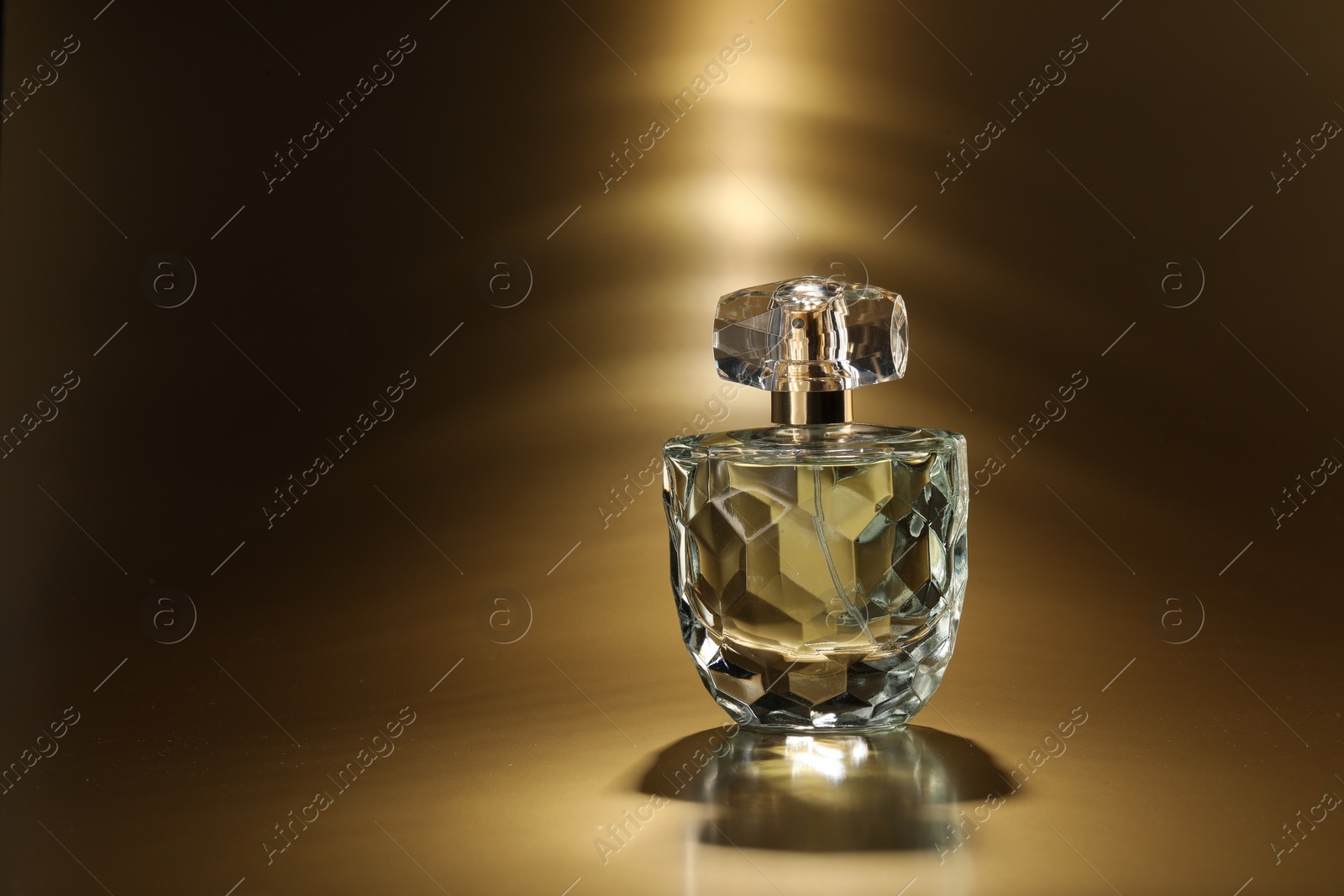 Photo of Luxury women's perfume. Sunlit glass bottle on golden background, space for text