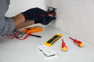 Electrician with screwdriver repairing power socket indoors, focus on plugs