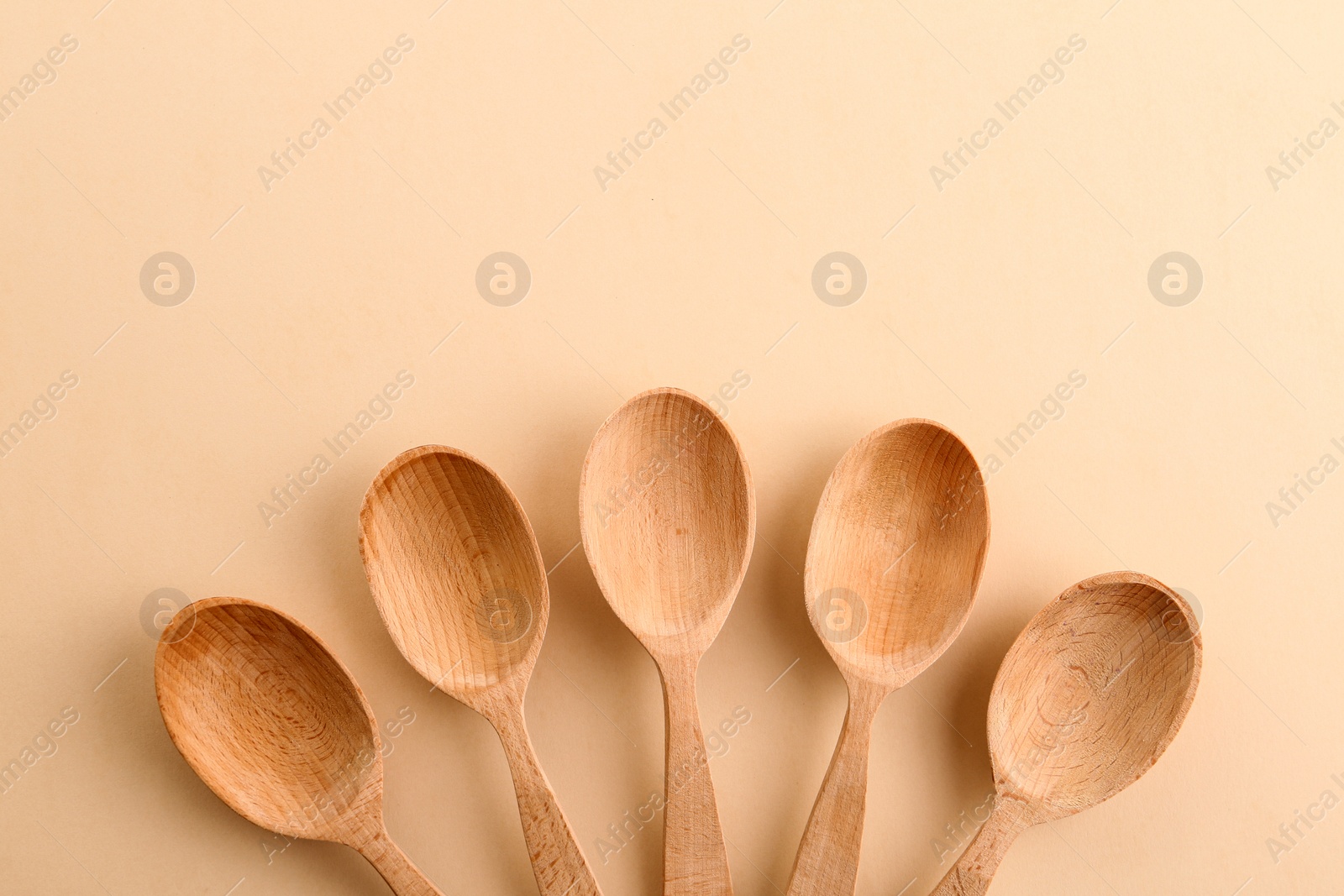 Photo of Flat lay composition with clean wooden spoons and space for text on color background