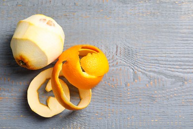 Photo of Peeled fresh orange with zest preparing for drying on wooden table, flat lay. Space for text
