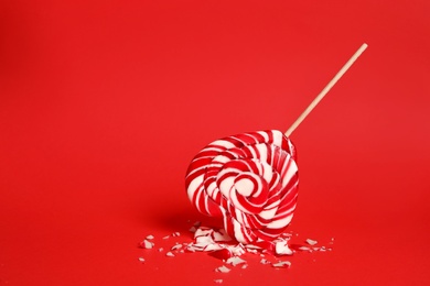 Photo of Broken heart shaped lollipop on red background, space for text. Relationship problems concept