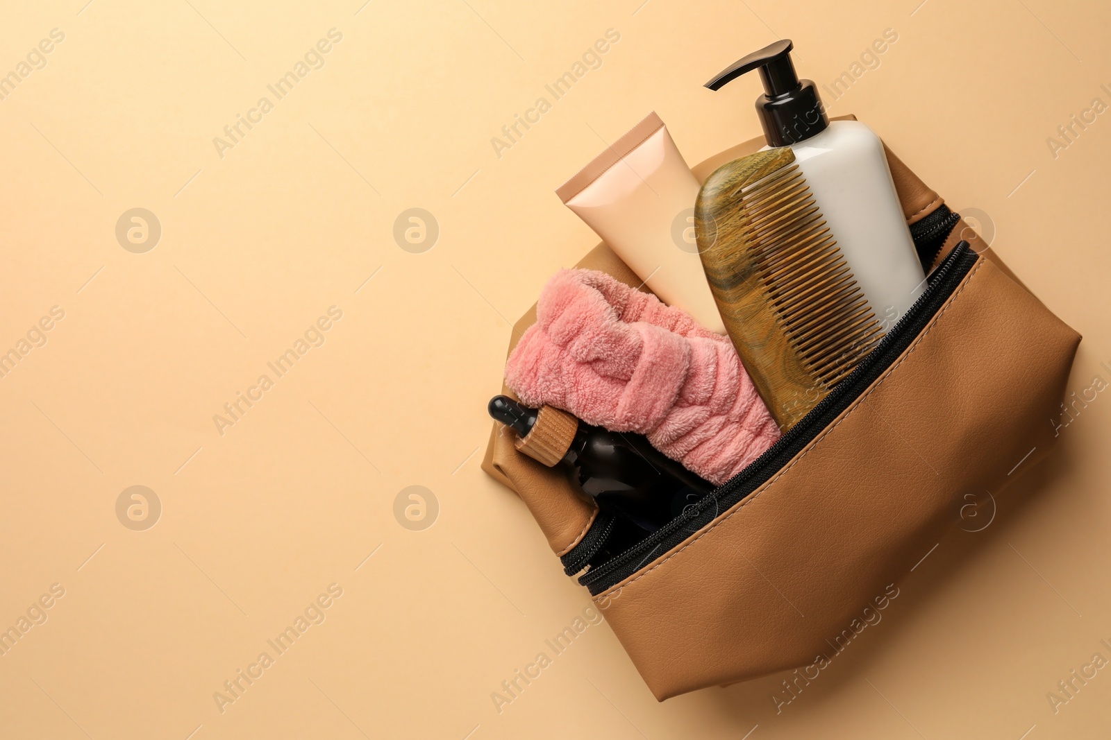Photo of Preparation for spa. Compact toiletry bag with different cosmetic products on beige background, top view. Space for text
