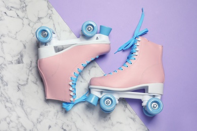 Photo of Pair of stylish quad roller skates on color background, top view