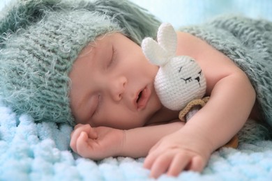 Cute newborn baby sleeping on light blue blanket, closeup