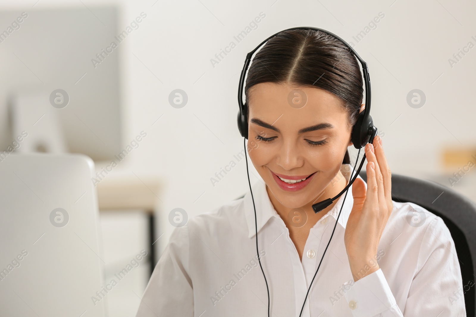 Photo of Hotline operator with headset working on computer in office