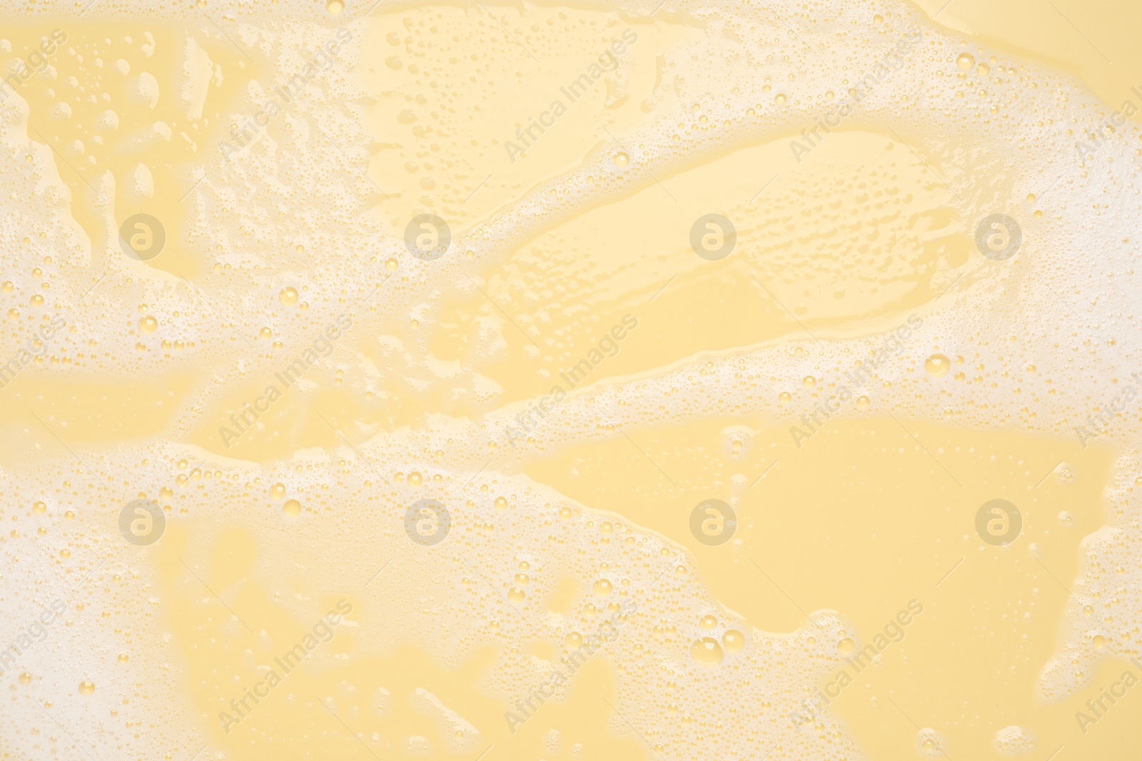 Photo of White washing foam on yellow background, top view