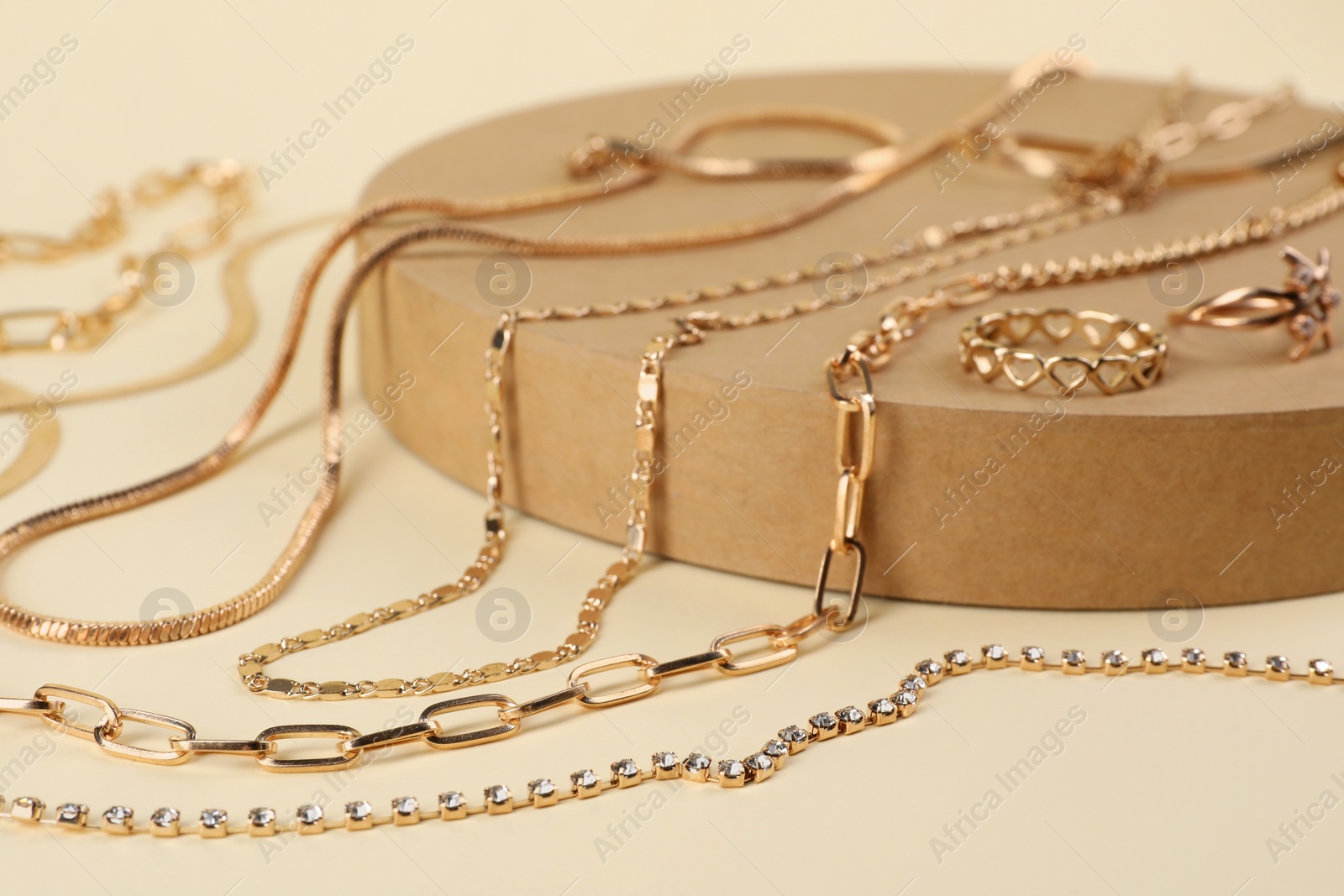 Photo of Metal chains and other different accessories on beige background, closeup. Luxury jewelry