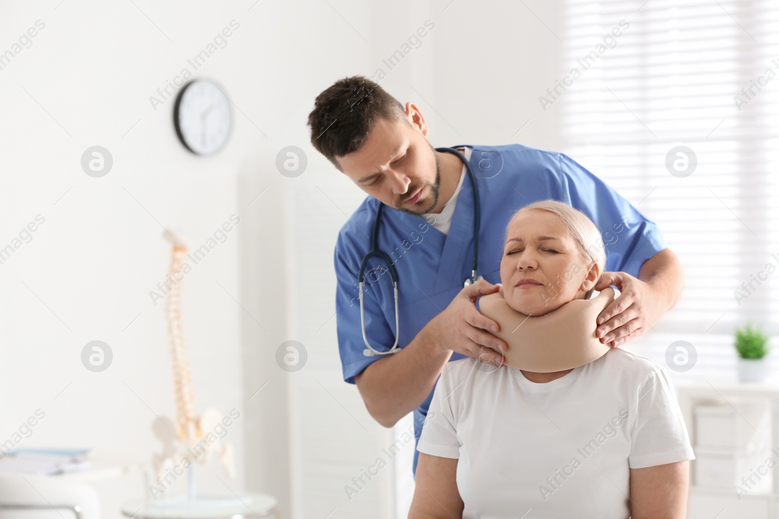 Photo of Orthopedist applying cervical collar onto patient's neck in clinic